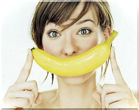 Woman holding banana in front of her mouth