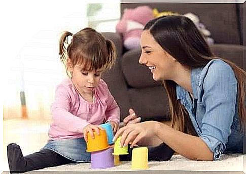 A woman and a little girl playing on the rug.