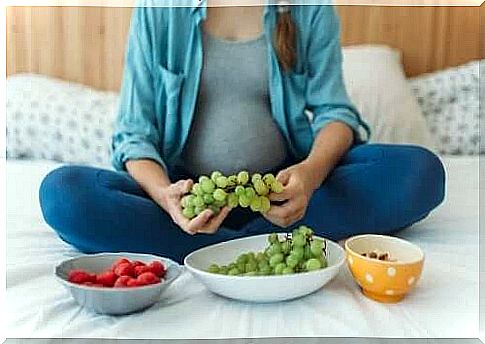 Safe medication: A woman sitting on a bed with three bowls of fruit in front of her.